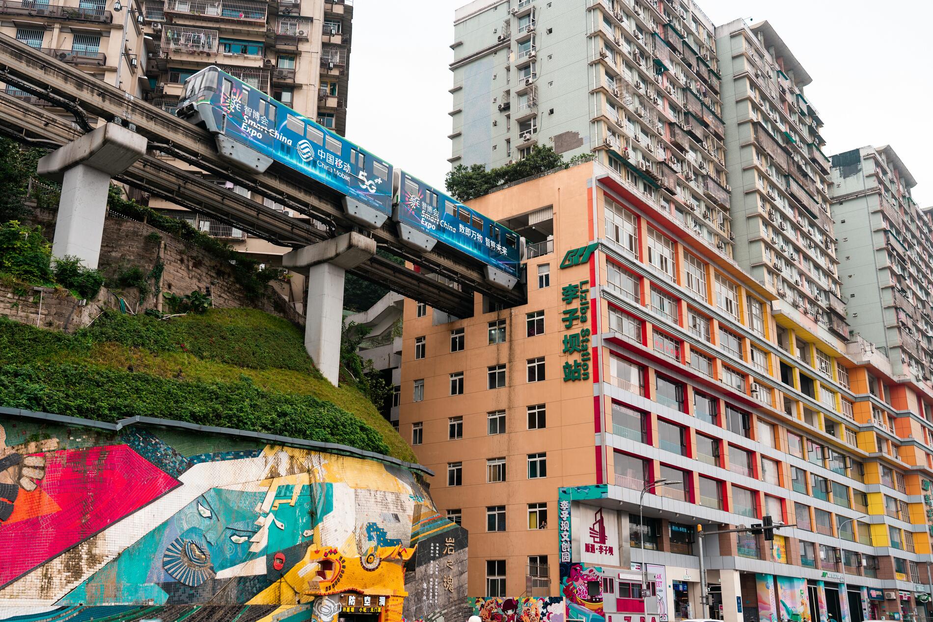 Die Architektur entzieht sich jeder Logik: Der Zug der Monorail-Linie 2 fährt buchstäblich durch das Innere eines Wohnhauses am Bahnhof Liziba. Acht Stockwerke hoch und ohne jede Erschütterung oder Störung ist sie ein perfektes Beispiel dafür, wie diese vertikale Stadt jedes Hindernis in eine futuristische Lösung verwandelt. Foto: Darmau. Foto Darmau. Chongqing. China.